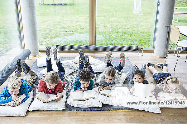 Pupils lying on the floor reading books in school break room