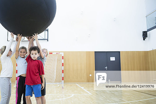Pupils holding big ball in gym class