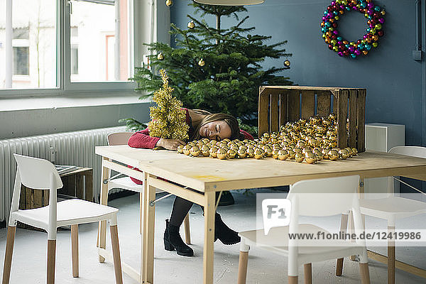 Woman sitting at table with many golden Christmas baubles