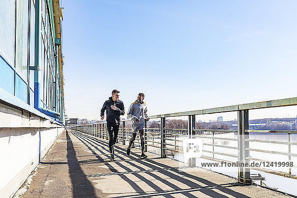 Friends running on a bridge in the city