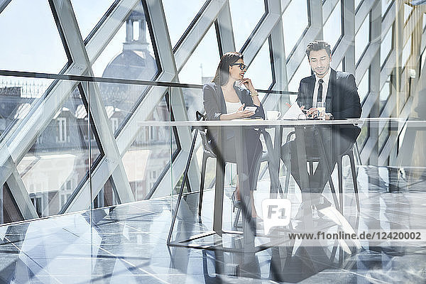 Businesswoman and businessman talking at desk in modern office