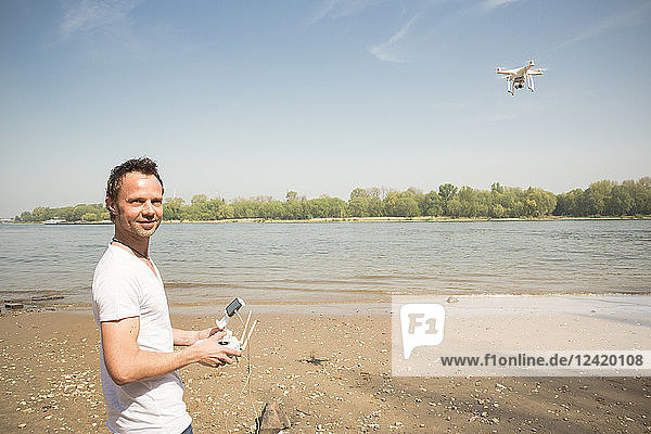 Portrait of smiling man flying drone at a river