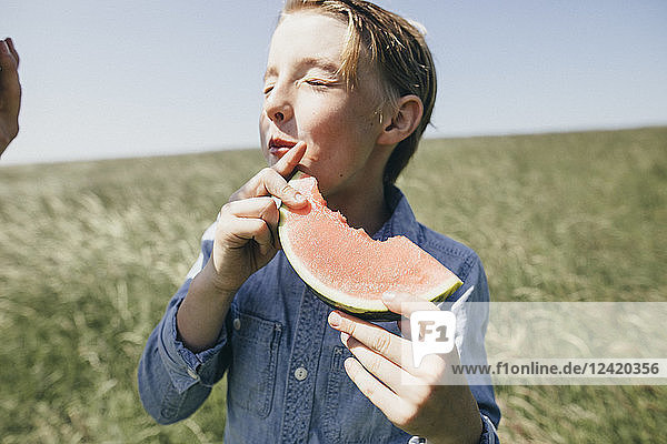 Boy on a field eating a watermelon