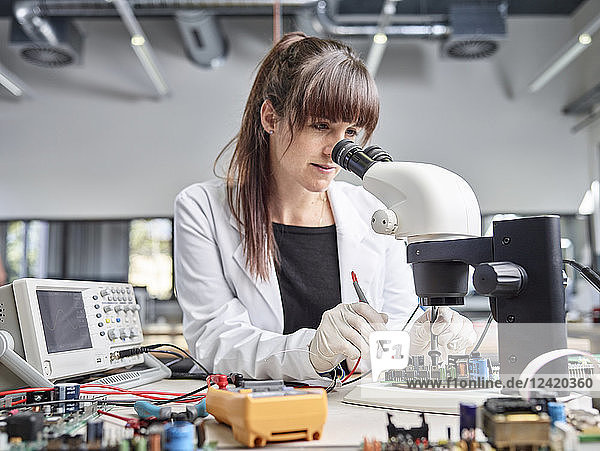 Female technician checking circuit board
