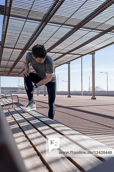 Sportive man having a break on a bench under roofing