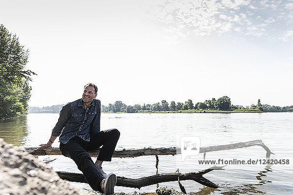 Mature man sitting at Rhine riverbank