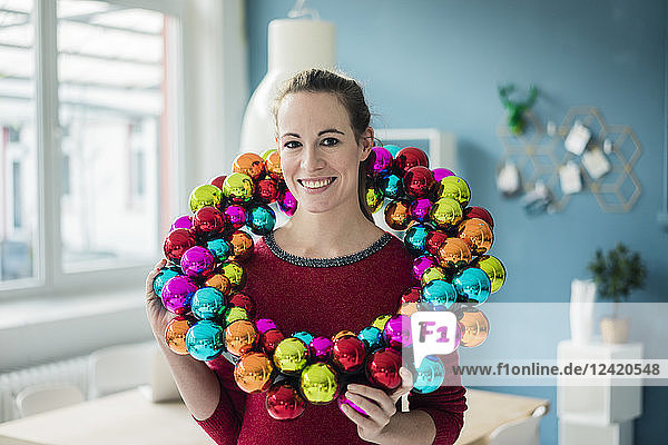 Portrait of smiling woman with colourful Christmas bauble wreath