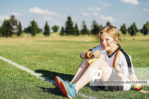 Boy wearing German soccer shirt  blowing horns on soccer field