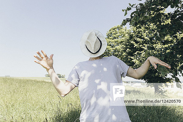 Man covering his face with a hat in field