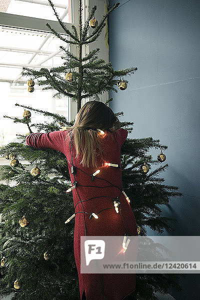 Back view of woman hugging Christmas tree