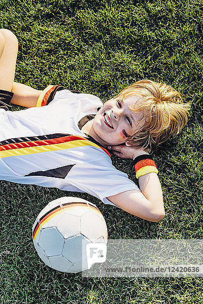 Boy in German soccer shirt lying on grass  smiling