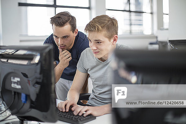 Teacher and student using computer in class