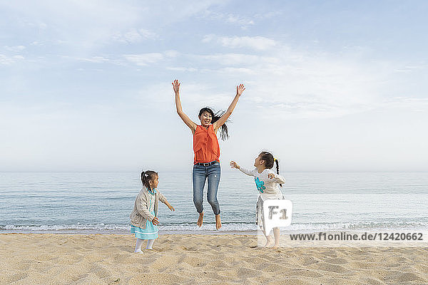 Happy mother with two daughters playing on the beach