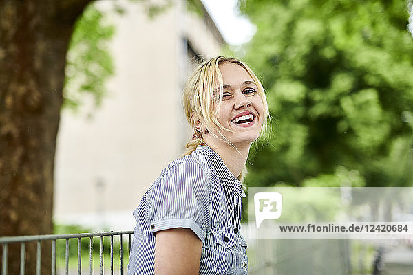 Laughing blond young woman at a fence
