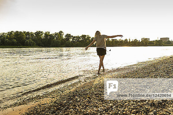 Young woman walking barefoot on riverside