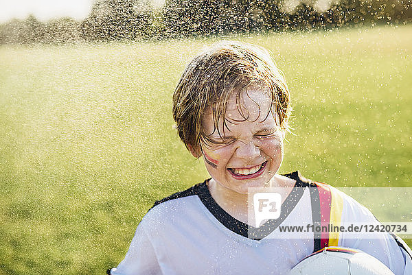 Boy wearing German soccer shirt standing in water splashes