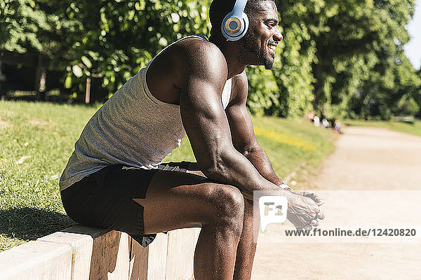 Smiling young athlete taking a break  wearing headphones  listening music