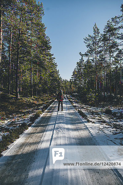 Sweden  Sodermanland  backpacker standing on path in remote forest in winter