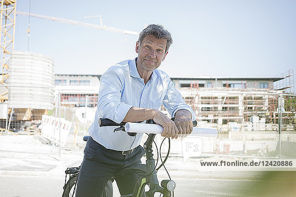 Portrait of man with e-bike on construction site