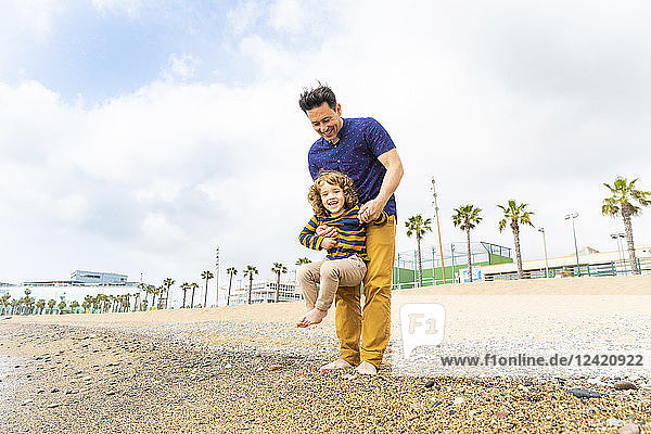 Spain  Barcelona  father holding his son on the beach