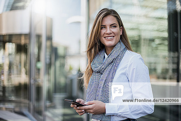 Portrait of smiling young businesswoman with smartphone