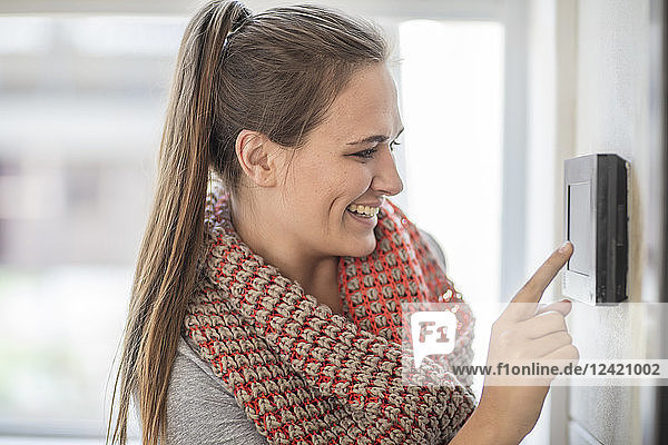 Smiling young woman using intercom in office