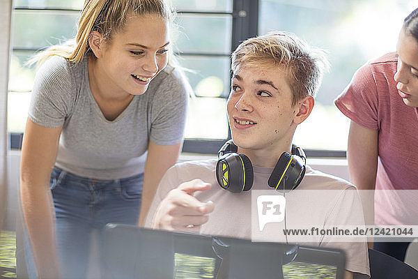 Teenage girls talking to boy using laptop
