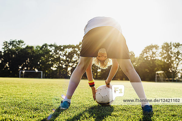 Boy on soccer field  bending over  looking through his legs