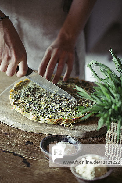 Young woman slicing homemade chickpea and herb cake