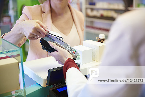 Customer paying cashless with credit card in a pharmacy