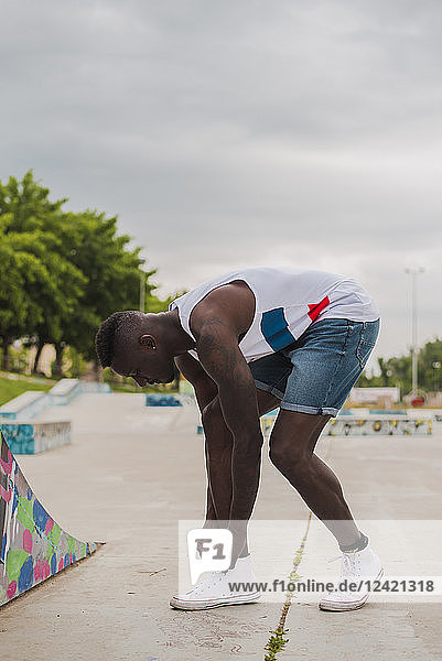 Young man in skatepark  tying shoes