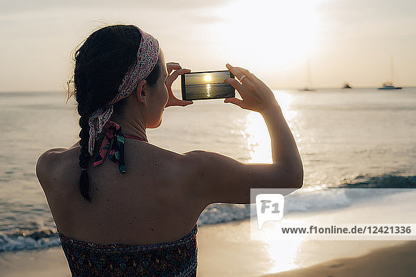 Thailand  Koh Lanta  woman on the beach taking photo with cell phone at sunset