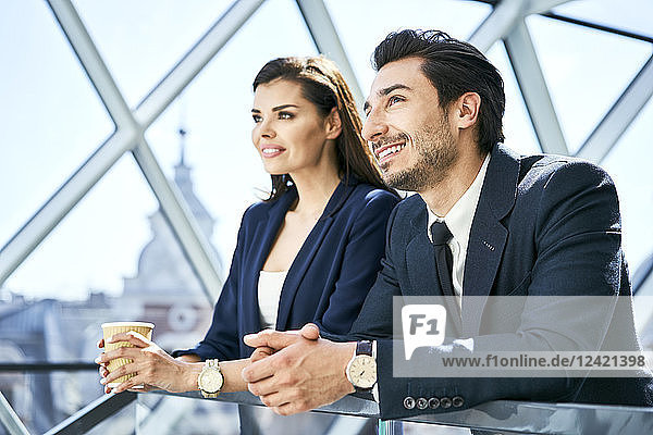 Smiling businesswoman and businessman having a coffee break in modern office
