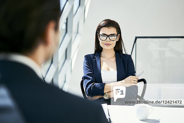 Portrait of confident businesswoman with businessman in modern office