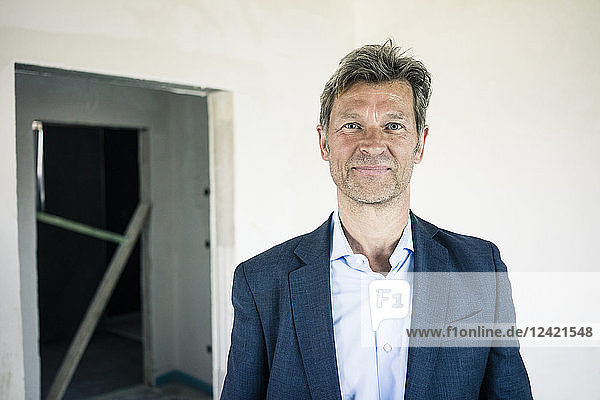Portrait of smiling man in suit in building under construction