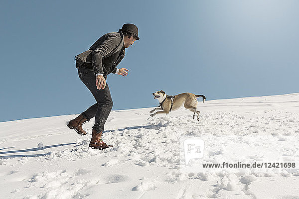 Man playing with dog in winter  throwing snow