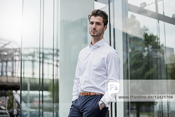 Businessman leaning against glass facade