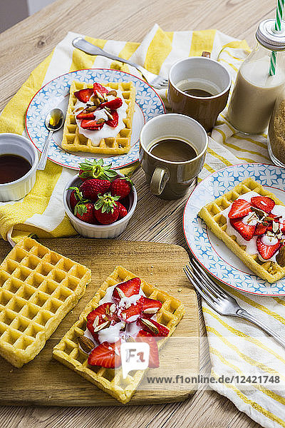 Waffles garnished with strawberries  Greek yogurt and almonds on breakfast table