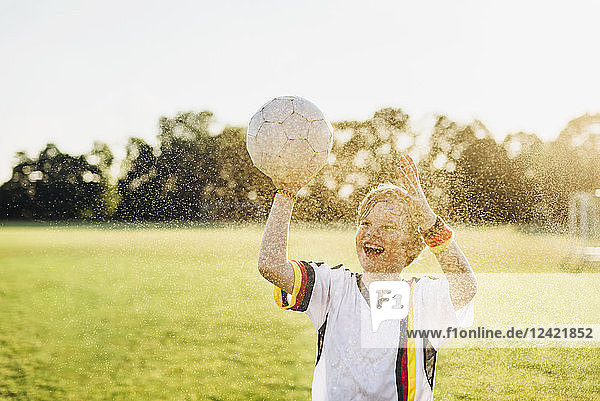 Boy wearing German soccer shirt screaming for joy  standing in water splashes