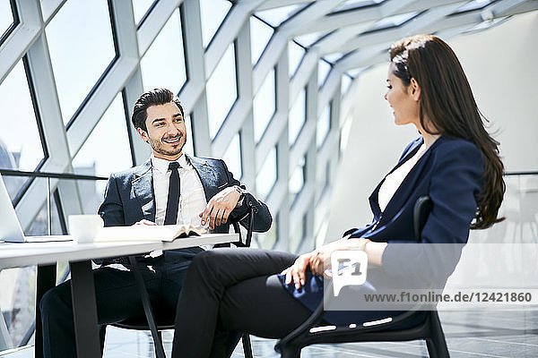 Businesswoman and businessman talking at desk in modern office