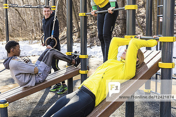 Friends exercising at fitness equipment in a park
