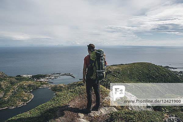 Norway  Lofoten  Moskenesoy  Backpacker standing on cliff  looking to the Atlantic Ocean