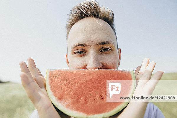 Portrait of a young man holding a watermelon outdoors