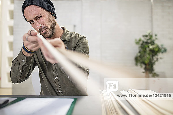 Young man working with wood at desk in office