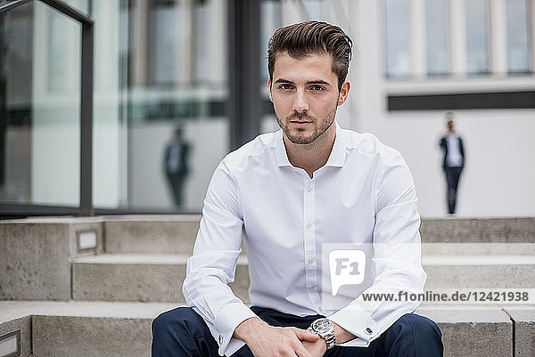 Portrait of young businessman sitting on stairs