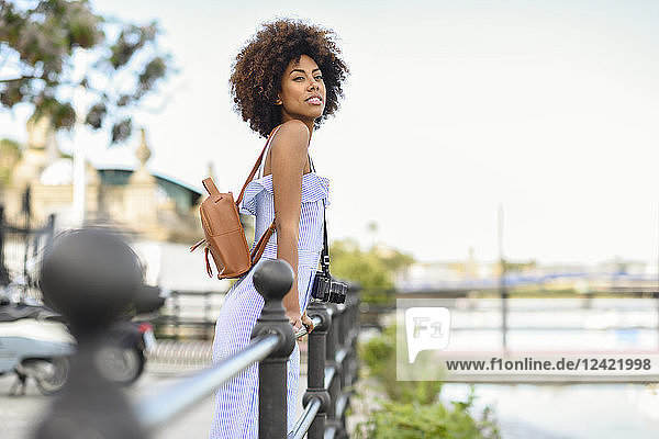 Portrait of fashionable young woman with camera and backpack