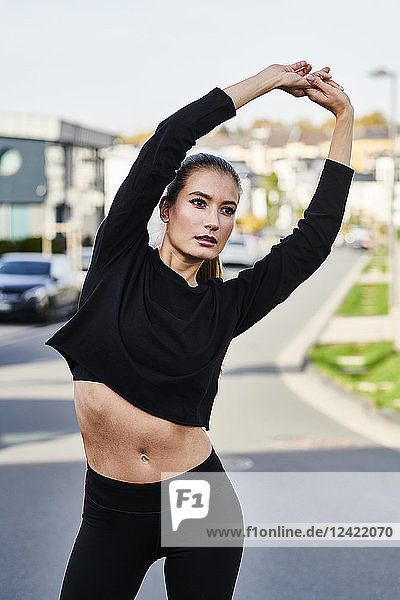 Sportive young woman stretching on a street in the city