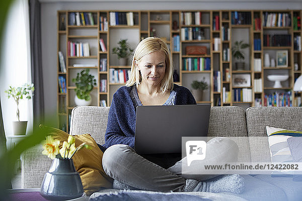 Woman at home sitting on couch using laptop