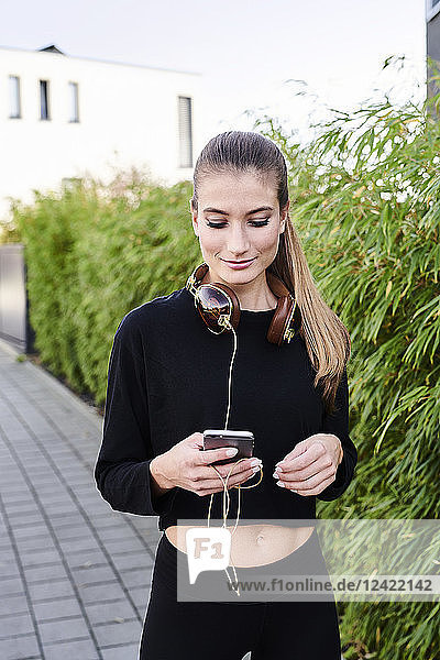 Sportive young woman with headphones and cell phone outdoors