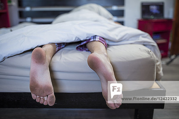 Dirty feet of boy lying in bed
